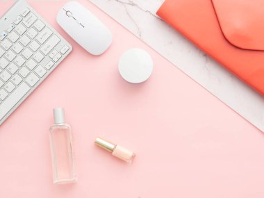 Düz, pembe masa çerçevesinin üst görüntüsü. Dizüstü bilgisayarı, kırmızı klasör debriyajı, şifalı kozmetik, bilgisayar klavyesi ve faresi olan kadınsı çalışma alanı kopyalama alanı olan pembe bir arkaplanda izole edilmiş.
