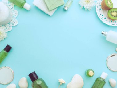 Doğal erkeksi kozmetik konsepti. Taze şakayık çiçekleri yeşil kivi dilimleri, vücut jeli, el yapımı sabun aromalı meyvemsi aromalı mavi kağıt rengi arka plan. Düz görünüm kopyalama alanı