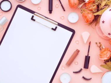 Klavye faresi, bir fincan çay ve makyaj malzemeleri ve pembe şeftali rengi arka planda izole edilmiş kozmetik ürünler. Düz konum, üst görünüm kopyalama alanı. Kadınsı güzellik blogcusu iş yeri kavramı.