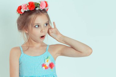 Şok olmuş bir kız çocuğu kulak misafiri olup şok edici haberler dinliyor. Beyaz mavi gri arka planda izole edilmiş çiçek tokalı beyaz çocuk modelinin yakın plan portresi. Yatay resim