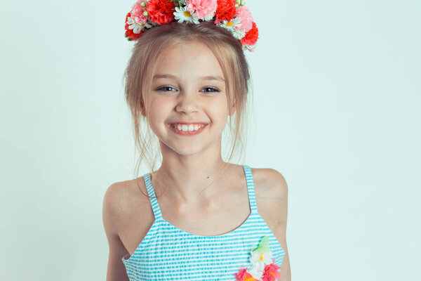 Cute kid girl smiling looking, laughing at you camera happy posing. Closeup portrait of Caucasian kid model with floral headband isolated on white light green copy space background. Horizontal image