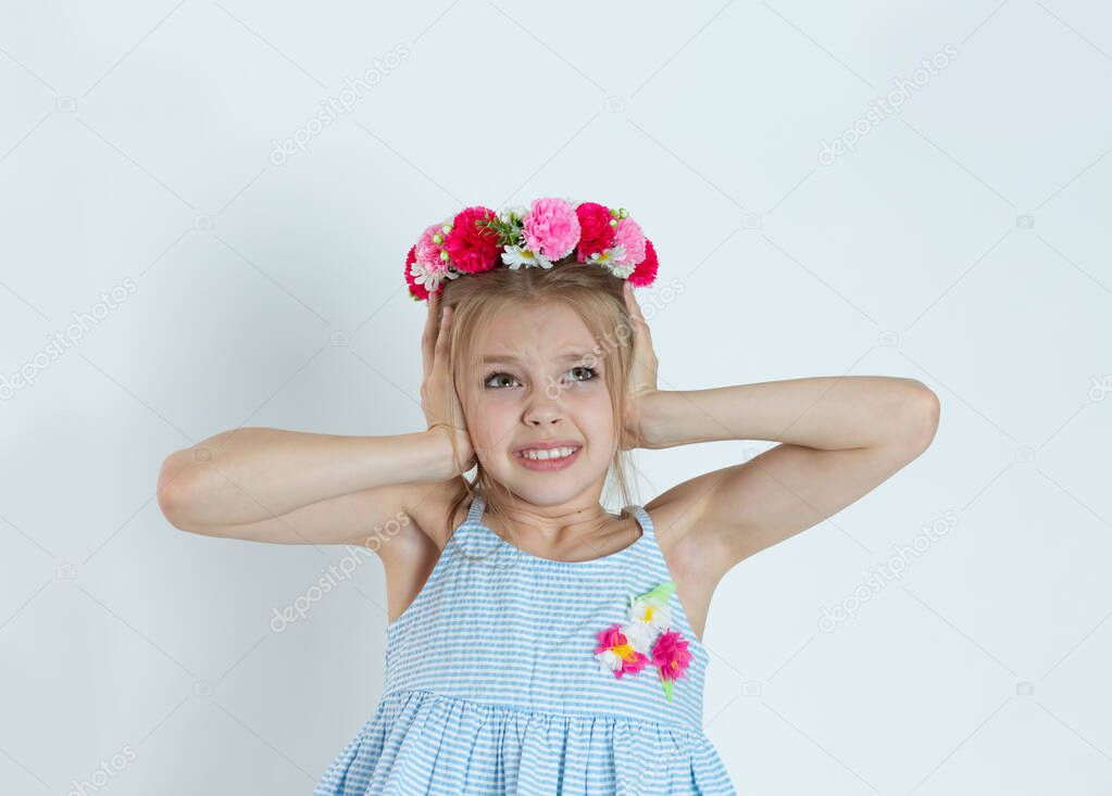 Angry unhappy stressed girl, kid covering her ears looking up stop making loud noise it's giving me headache isolated on light blue white wall background. Negative emotion face expression feeling