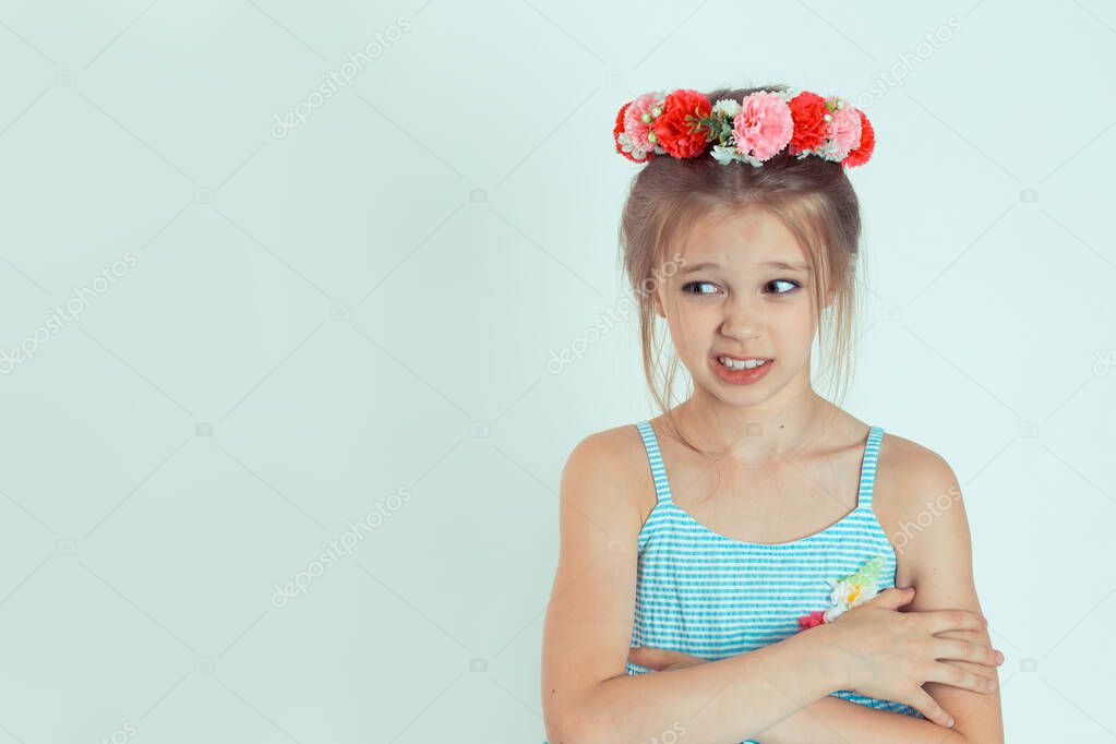 Portrait of young girl, kid in an awkward situation, playing nervously with hands looking to the side with skeptical doubtful funny look isolated on white-green background