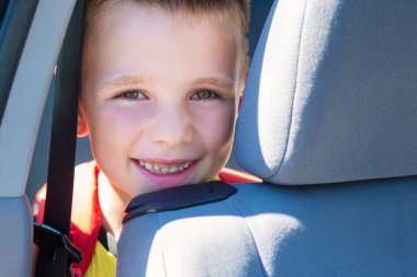 Mutlu küçük çocuk arabada oturmuş kameraya bakıyor mutlu bir şekilde gülümsüyor.