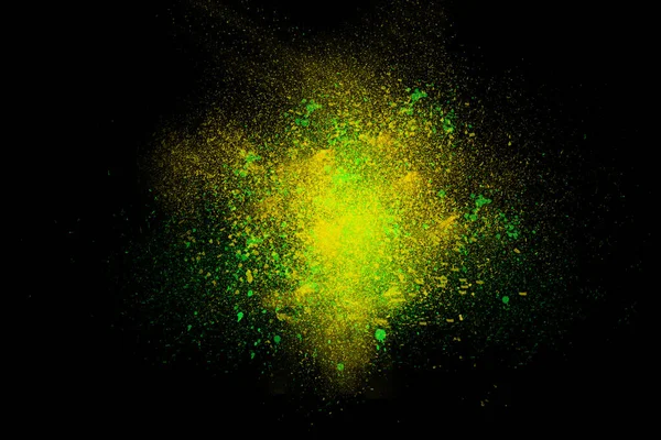 Freeze motion of colorful powder exploding, isolated on black, dark background. Abstract design of dust cloud. Particles explosion, screen saver wallpaper with copy space. Vivid green yellow ash