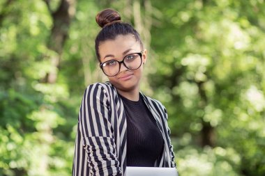 Kafası karışmış bir öğrenci. Yakın plan portresi kafası karışık genç bir kadının koluna taktığı sorunun ne olduğunu soruyordu. Yani arka planda izole edilmiş yeşil park ağaçlarını bilmiyorum. Olumsuz duygu yüz ifadesi