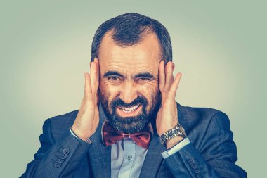 Başı ağrıyan, hayal kırıklığı içinde el ele tutuşan işadamı, açık yeşil arka planda izole edilmiş ve sarı gradyan ile izole edilmiş sinirli bir şekilde üzgün. Negatif insan duyguları