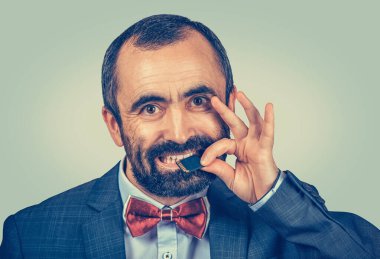 Dış hafıza konsepte ihtiyaç duyar. Zarif ceket giyen sakallı bir iş adamı portresi ve yeşil arka planda izole edilmiş mikro SD kartı tutan kırmızı papyon. İnsan yüzü ifadesi