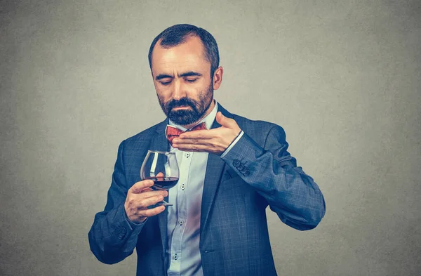Business man smelling a glass of wine, man wine feeling his aroma in studio. Mixed race bearded model isolated on grey gray gradient background. Positive emotion