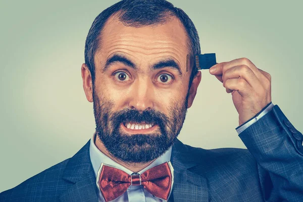 External memory needed concept. Portrait of angry bearded businessman wearing elegant jacket and red bow tie holding Micro SD card near his head isolated on green background. Human face expression
