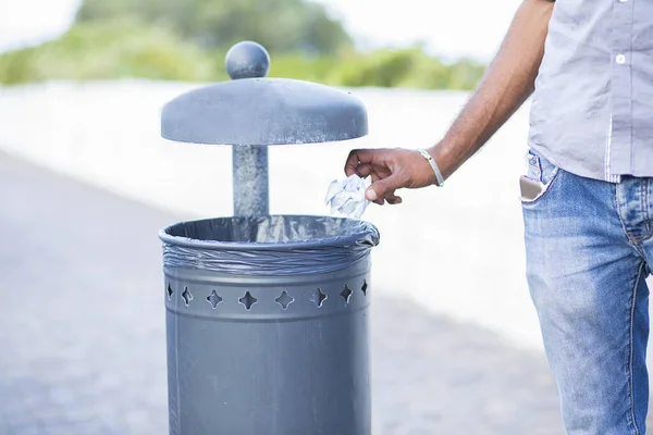 Man, unrecognisable person throwing trash in recycling bin, isolated outside seaside tropical background. Recycling, eco friendly approach concept. Keep streets, city, earth clean