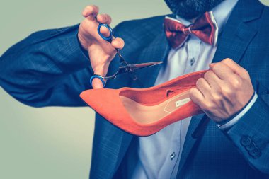 Ayakkabı ve makas tutan orta yaşlı bir adam onları stüdyoda kesmek üzere. Yeşil sarı eğimli arka planda izole edilmiş melez sakallı model. Pozitif duygu