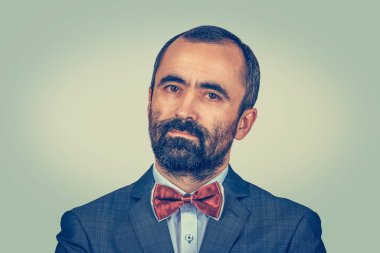 Yakın plan mutlu genç adam portresi. Stüdyoda sakallı hippi bir erkek resmi olarak giyiniyor. Yeşil sarı eğimli arka planda izole edilmiş melez sakallı model. Pozitif duygu