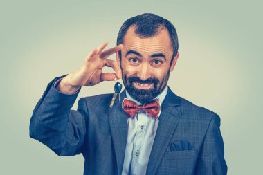 Araba ya da evin anahtarlarını veren vahşi sakallı, olgun, orta yaşlı bir adamın portresi. Yeşil sarı eğimli arka planda izole edilmiş melez sakallı model. Pozitif duygu