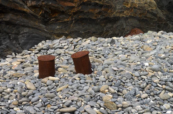Tacchetti di ormeggio arrugginiti usati come sgabelli sulle pietre della spiaggia — Foto Stock