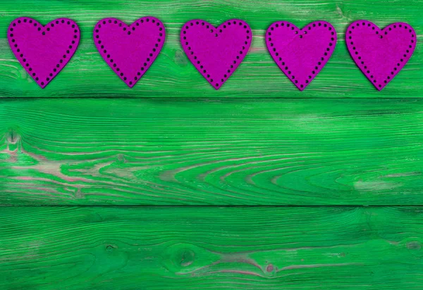 Розовые сердца на зеленом деревенском деревянном фоне с текстурой древесины — стоковое фото