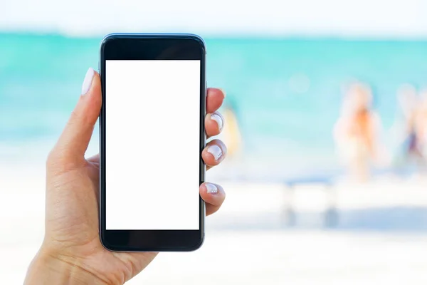 Bella mano di donna utilizzando smartphone in spiaggia. Smartphone schermo bianco. Schermo vuoto vuoto — Foto Stock