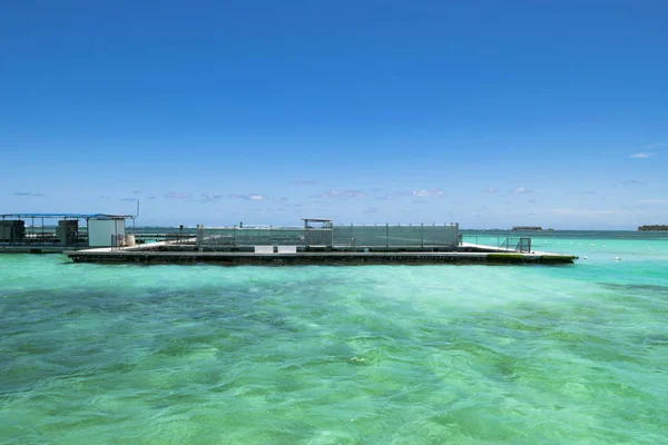 Fish farm in the turquoise ocean with small waves, blue sky background — Stock Photo, Image