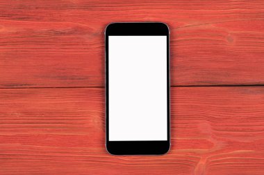 Boş ekran yukarı alay ile cep telefonu kırmızı ahşap masa arka plan üzerinde izole. Ahşap masa üstünde smartphone. Smartfone beyaz