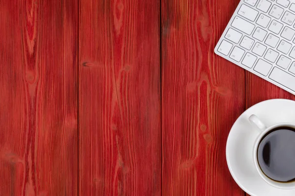 Escritorio de oficina con espacio para copias. Dispositivos digitales teclado inalámbrico y ratón en la mesa de madera roja con taza de café, vista superior — Foto de Stock