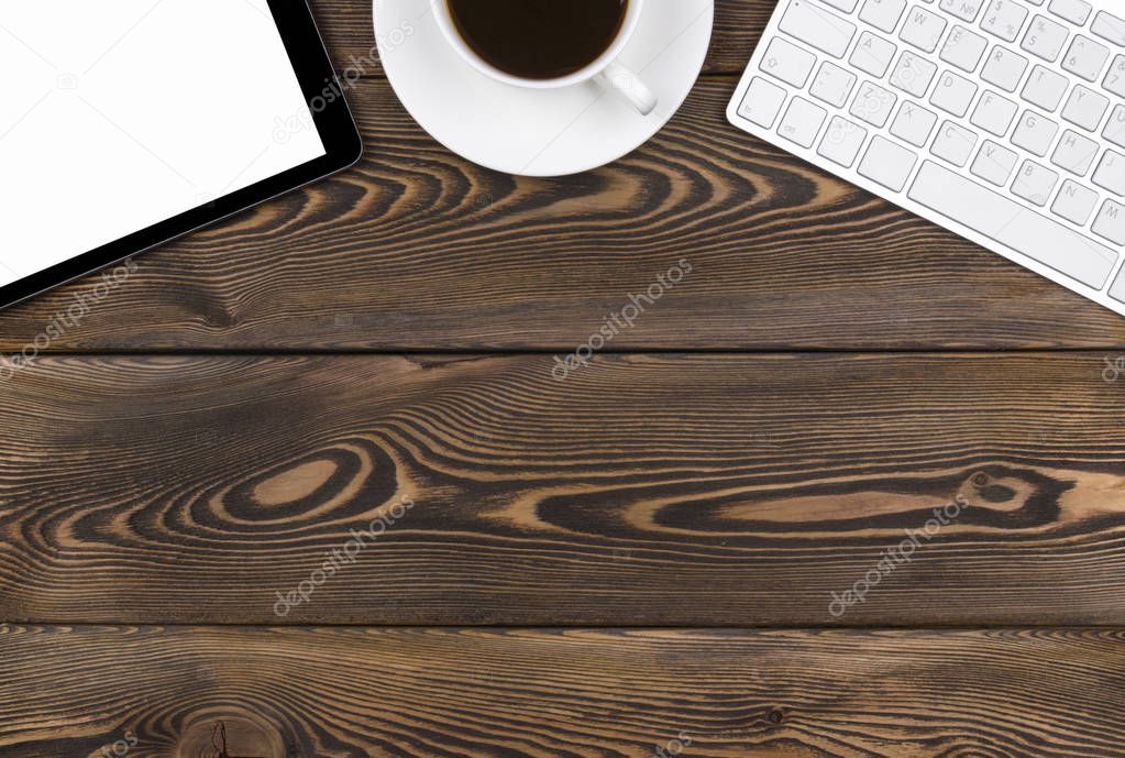 Office desk with copy space. Digital devices wireless keyboard, mouse and tablet computer with empty screen on dark  wooden table with cup of coffee, top view