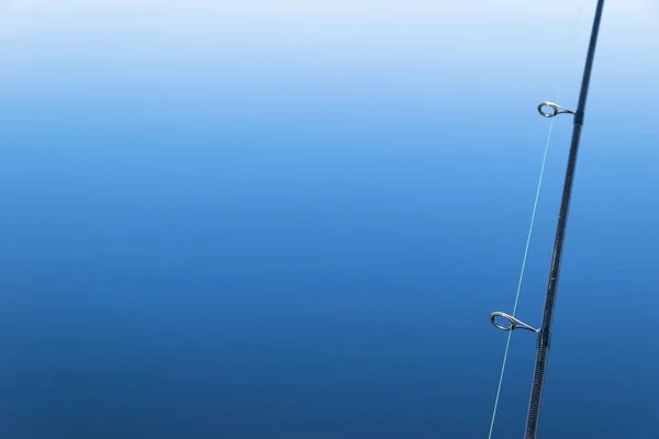 Pesca en el barco con caña de arrastre y carrete. Fondo azul marino —  Fotos de Stock