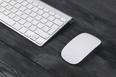 Eski siyah ahşap masa arka plan üzerinde kablosuz bilgisayar klavye, fare ve anahtarları bir iş çalışma alanı'nın görünümünü kapat