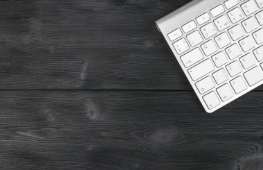 Kablosuz bilgisayar klavye ile bir iş çalışma alanı'nın görünümü kadar eski siyah ahşap masa arka plan üzerinde tuşları kapatmak