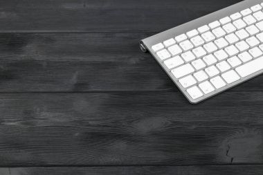 Kablosuz bilgisayar klavye ile bir iş çalışma alanı'nın görünümü kadar eski siyah ahşap masa arka plan üzerinde tuşları kapatmak