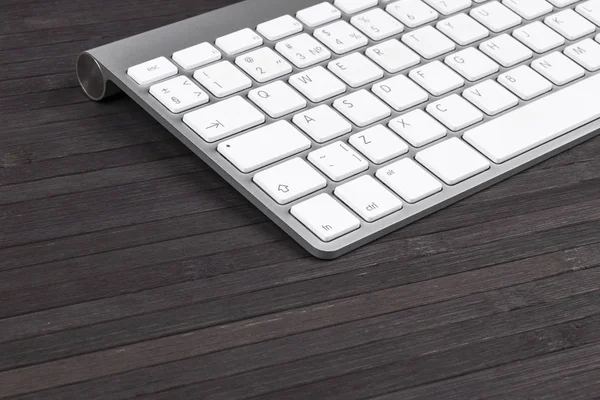 Vista de cerca de un lugar de trabajo de negocios con teclado inalámbrico de computadora, teclas en el fondo de mesa de madera negro viejo. Escritorio de oficina con espacio de copia — Foto de Stock