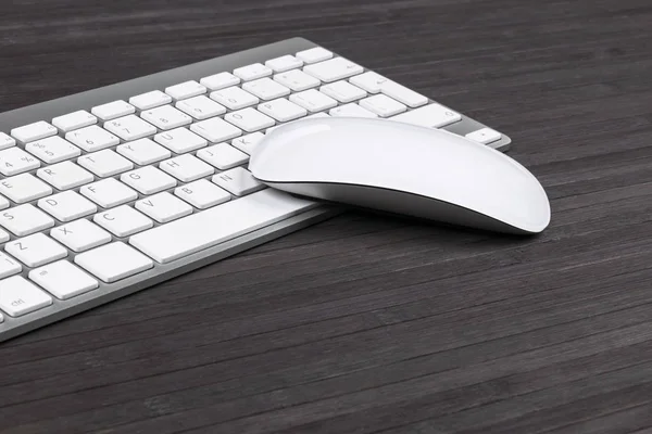 Vista de cerca de un lugar de trabajo de negocios con teclado de computadora inalámbrica, teclas y ratón en el fondo de mesa de madera oscura vieja. Escritorio de oficina con espacio de copia — Foto de Stock