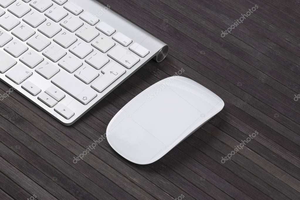 Close up view of a business workplace with wireless computer keyboard, keys and mouse on old dark wooden table background.  Office desk with copy space