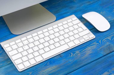 İş işyeri bilgisayar, kablosuz klavye ve fare üstünde eski mavi ahşap masa arka plan ile. Ofis Masası kopya alanı ile