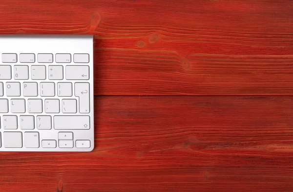 Vista de cerca de un lugar de trabajo de negocios con teclado inalámbrico de computadora, teclas sobre fondo de mesa de madera natural rojo viejo. Escritorio de oficina con espacio de copia — Foto de Stock