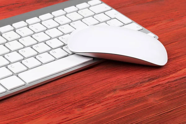 Vista de cerca de un lugar de trabajo de negocios con teclas de teclado de computadora inalámbrica y ratón sobre fondo de mesa de madera natural rojo viejo. Escritorio de oficina con espacio de copia — Foto de Stock