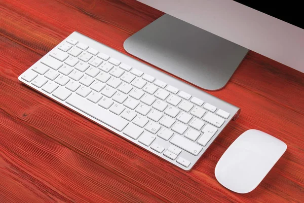 Lugar de trabajo de negocios con ordenador, teclado inalámbrico y ratón sobre fondo de mesa de madera rojo viejo. Escritorio de oficina con espacio de copia — Foto de Stock