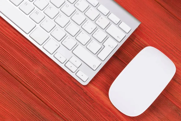 Lugar de trabajo de negocios con ordenador, teclado inalámbrico y ratón sobre fondo de mesa de madera rojo viejo. Escritorio de oficina con espacio de copia — Foto de Stock