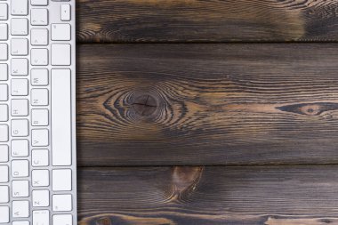 Kablosuz bilgisayar klavye ile bir iş çalışma alanı'nın görünümü kadar anahtarları eski karanlık doğal ahşap masa arka plan üzerine kapatın. Ofis Masası kopya alanı ile
