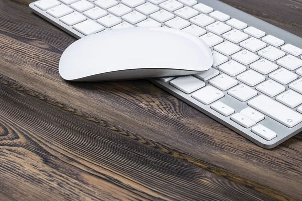 Vista de cerca de un lugar de trabajo de negocios con teclado de computadora inalámbrica, teclas y ratón en el fondo de mesa de madera natural oscuro viejo. Escritorio de oficina con espacio de copia — Foto de Stock