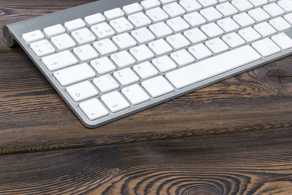 Vista de cerca de un lugar de trabajo de negocios con teclado de computadora inalámbrica, teclas en el fondo de mesa de madera natural oscuro viejo. Escritorio de oficina con espacio de copia — Foto de Stock