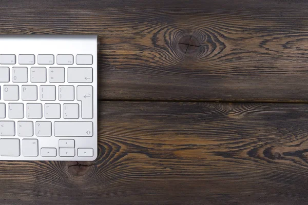 Vista de cerca de un lugar de trabajo de negocios con teclado de computadora inalámbrica, teclas en el fondo de mesa de madera natural oscuro viejo. Escritorio de oficina con espacio de copia — Foto de Stock