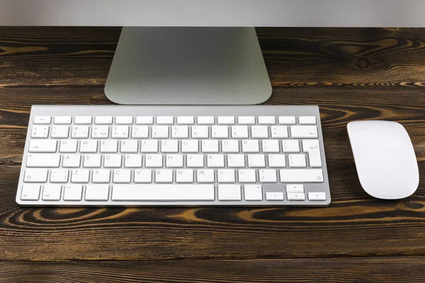 Vista de cerca de un lugar de trabajo de negocios con computadora, teclado inalámbrico, teclas y ratón en el fondo de mesa de madera oscura vieja. Escritorio de oficina con espacio de copia — Foto de Stock