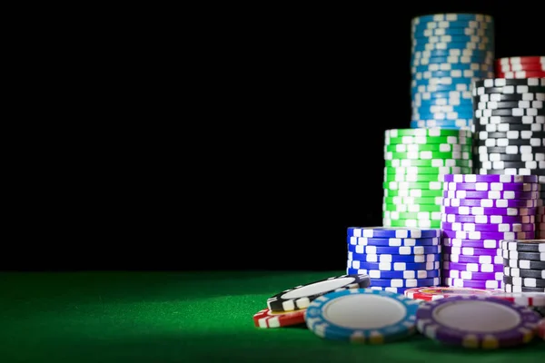Ένα σύνολο στοίβα μαρκών πόκερ σε ένα πράσινο τραπέζι παιχνίδι με ζάρι ρολά. Μαύρο φόντο. έννοια του κινδύνου - παίζοντας πόκερ στο καζίνο. Θέμα παιχνίδι πόκερ. — Φωτογραφία Αρχείου