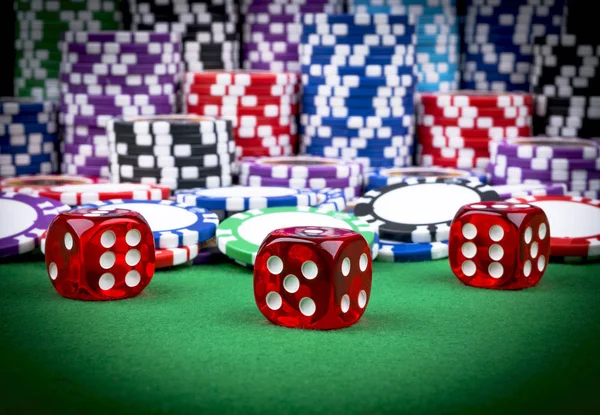 Ένα σύνολο στοίβα μαρκών πόκερ σε ένα πράσινο τραπέζι παιχνίδι με ζάρι ρολά. έννοια του κινδύνου - παίζοντας πόκερ στο καζίνο. Θέμα παιχνίδι πόκερ. Κόκκινο Καζίνο ζάρια. — Φωτογραφία Αρχείου