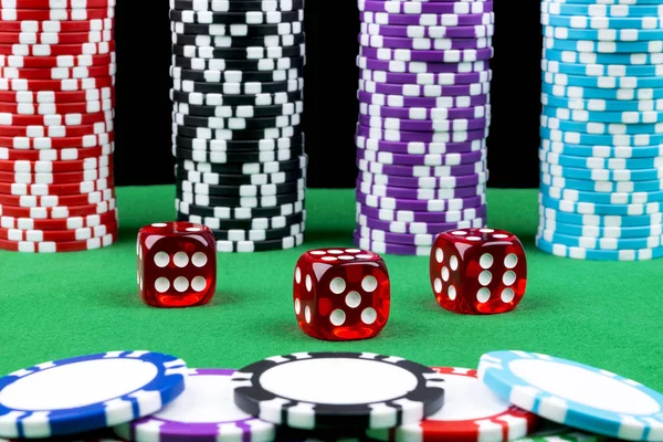 Ένα σύνολο στοίβα μαρκών πόκερ σε ένα πράσινο τραπέζι παιχνίδι με ζάρι ρολά. Μαύρο φόντο. έννοια του κινδύνου - παίζοντας πόκερ στο καζίνο. Θέμα παιχνίδι πόκερ. Κόκκινο Καζίνο ζάρια. — Φωτογραφία Αρχείου