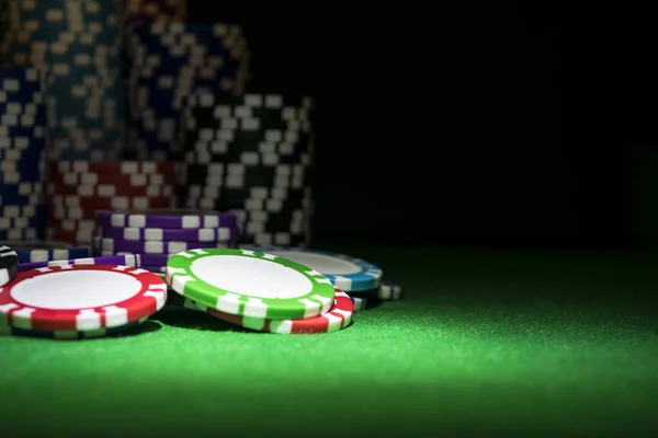 Ένα σύνολο στοίβα μαρκών πόκερ σε ένα πράσινο τραπέζι παιχνίδι με ζάρι ρολά. Μαύρο φόντο. έννοια του κινδύνου - παίζοντας πόκερ στο καζίνο. Θέμα παιχνίδι πόκερ. — Φωτογραφία Αρχείου