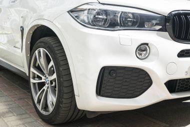  BMW X 5 M Perfomance. Lastik ve alaşım jant. Far. Beyaz modern lüks bir spor araba önden görünümü. Araba dış detaylar