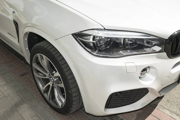 Představení BMW X 5 M. Pneumatiky a slitiny kolo. Světlometů. Čelní pohled na bílé moderní luxusní sportovní auto. Detaily exteriéru vozu — Stock fotografie