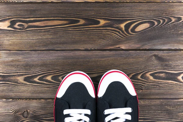 在木地板上的黑色和白色的鞋子的顶视图。鞋子在一个木制的背景上。在木地板上的运动鞋。体育、 健身、 鞋、 鞋类和对象的概念 — 图库照片