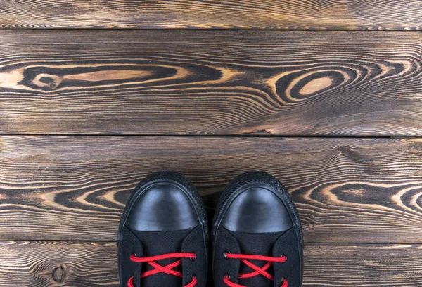 黑色的鞋子的木地板上的顶视图。鞋子在一个木制的背景上。在木地板上的运动鞋。体育、 健身、 鞋、 鞋类和对象的概念 — 图库照片